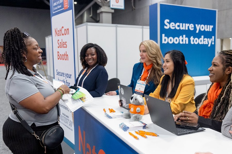 Natcon25 exhibit hall manager Alaina Herrera speaks with an attendee